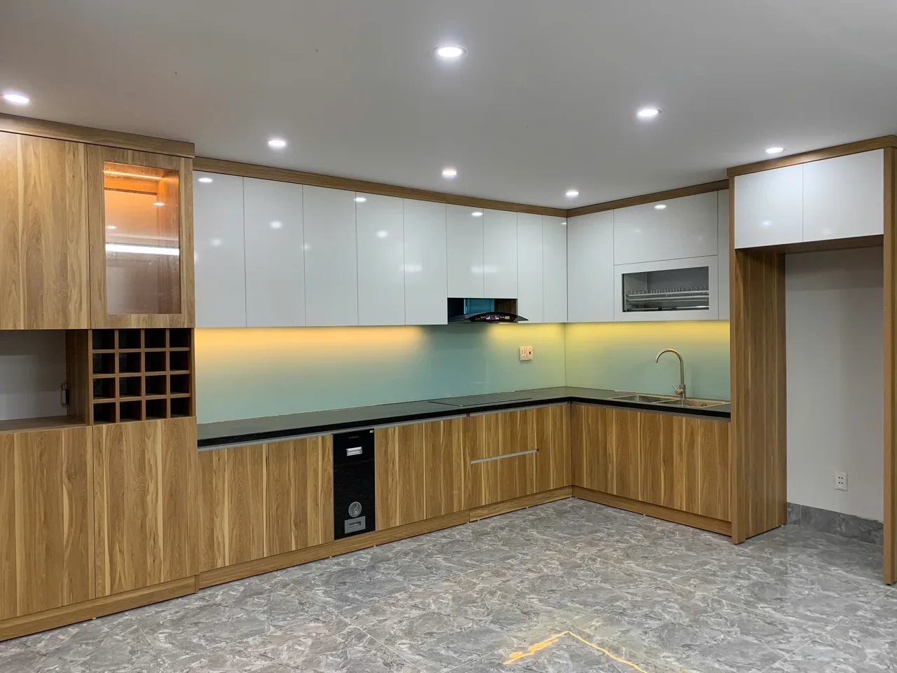 Tủ bếp chữ L phối cánh vân gỗ sáng, tủ trên trắng và ánh sáng ấm