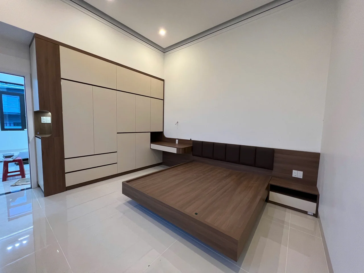 Phòng ngủ phối tủ áo màu kem với giường bục và tab đầu giường vân gỗ trầm