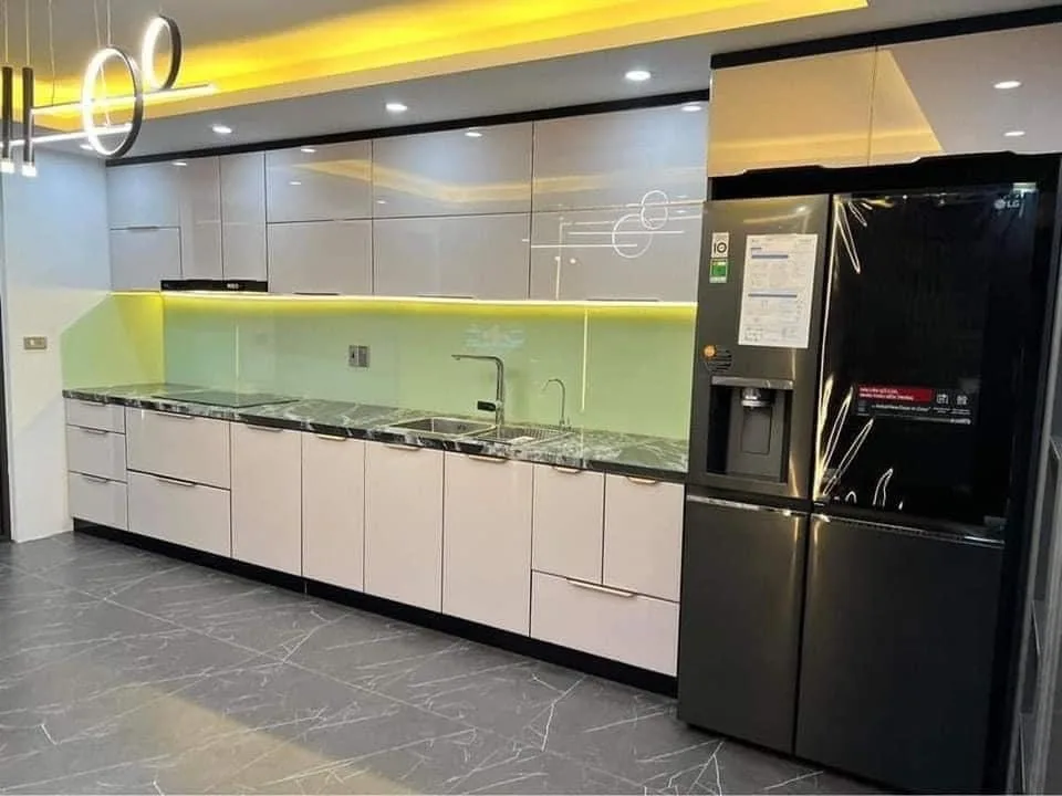 Tủ bếp cánh kính màu trắng kem phối mặt đá tối và kính ốp xanh