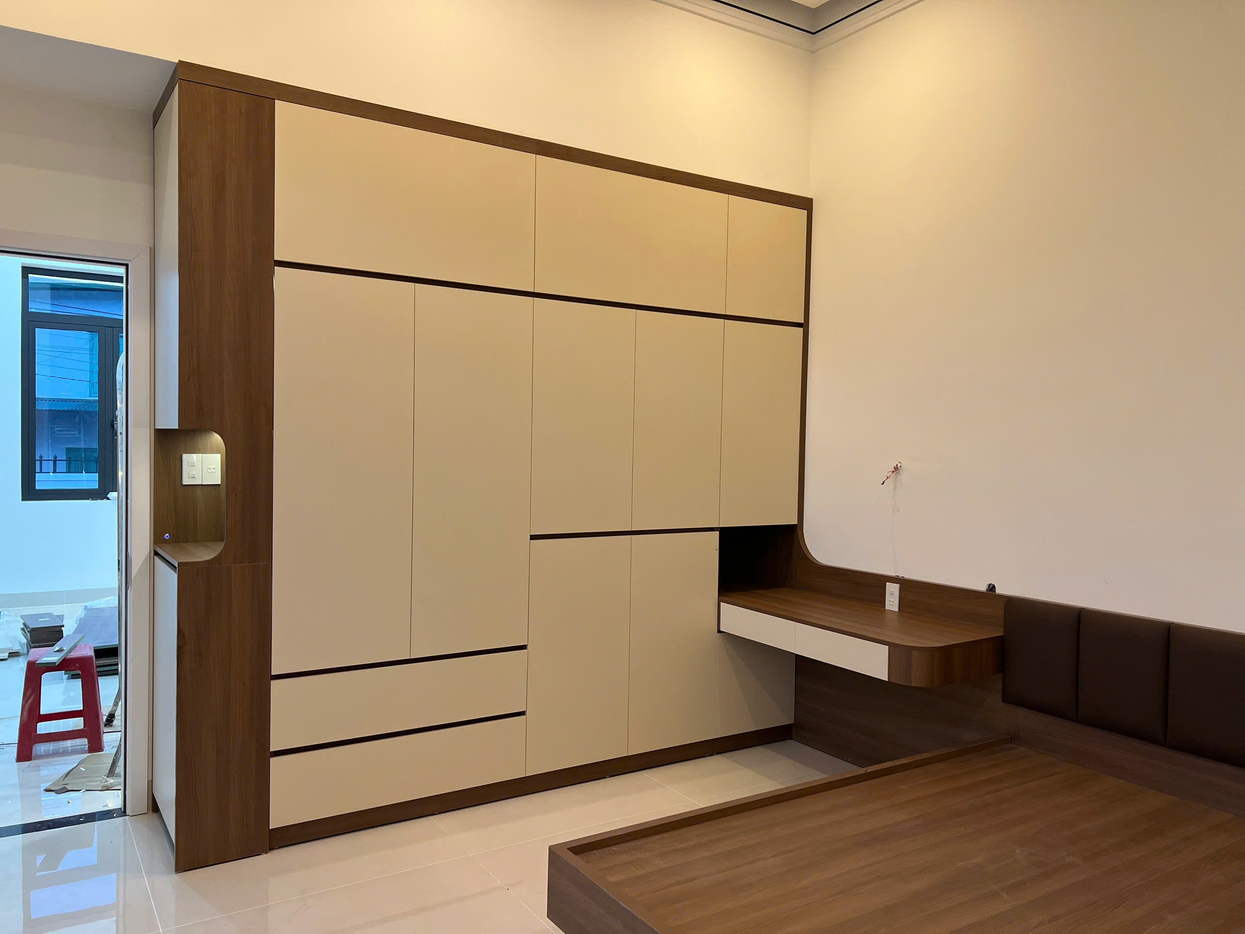 Phòng ngủ master gỗ MDF màu nâu đậm với vách ốp đầu giường và tủ áo cánh mở, góc nhìn 5